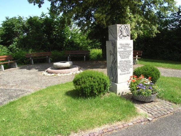 Im Vordergrund der Gedenkstein und dahinter der Brunnen